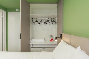 a bedroom with a bed and a closet with hangers at Easy Life Campus PUC by Xtay in Curitiba