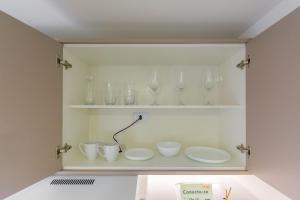 a shelf with glasses and cups on it at Easy Life Campus PUC by Xtay in Curitiba