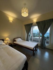 a bedroom with two beds and a large window at Sunset Villa in Coonoor