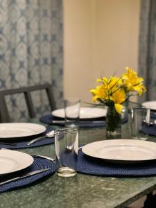 uma mesa com pratos e copos e um vaso com flores amarelas em Sunset Villa em Coonoor