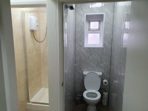 a small bathroom with a toilet and a shower at Mermaid Holiday Flats in Blackpool