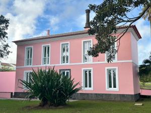 a pink house with a plant in front of it at Solar dos Cantos Botanic House & Garden in Ponta Delgada