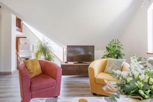 sala de estar con 2 sillas y TV en Les Glycines du Sommerberg en Niedermorschwihr