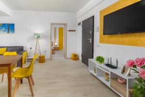 uma sala de estar com uma televisão e uma mesa e cadeiras em Curaçao Apartments - Building Stefan em Mamaia Nord – Năvodari