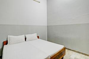 una piccola camera da letto con un letto con lenzuola bianche di Super OYO OYO Double Heart a Bhādra