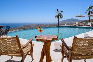 einen Tisch mit einem Glas Wein auf einem Pool in der Unterkunft Leon Luxury Suites in Imerovigli