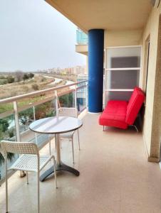 a balcony with a red couch and a table and chairs at Apartamento Moderno en Guardamar in Guardamar del Segura