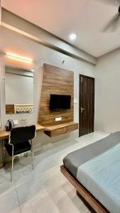 Schlafzimmer mit einem Bett, einem Schreibtisch und einem TV in der Unterkunft Hotel Evanka in Indore