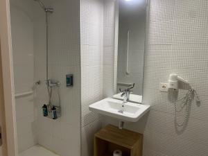 a white bathroom with a sink and a shower at Silken Casa Platerias Siglo XV in Zaragoza