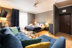 a living room with a blue couch and a bed at Wine & Wellness hotel Besední dům in Valtice