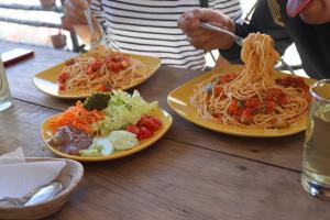 una mesa con tres platos de espagueti y verduras en Vrindavan Perú Jardín Ecológico en Matucana