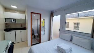 a bedroom with a bed and a kitchen with a window at Flat 01 in Jaguariaíva