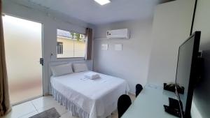 a small bedroom with a white bed and a window at Flat 01 in Jaguariaíva