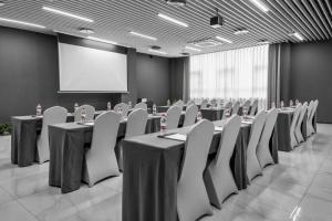 una sala de conferencias con mesas, sillas y una pantalla en Veegle By Landison Ningbo, en Ningbo