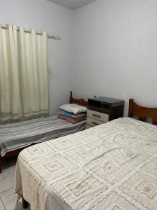 a bedroom with two beds and a dresser and a window at Beleza e praticidade no bairro Mirante in Santa Cruz Cabrália