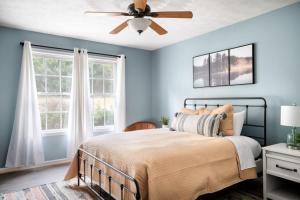- une chambre avec des murs bleus et un lit avec un ventilateur de plafond dans l'établissement Modern Cottage Hot Tub River Access Fire Pit, à Luray