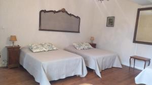 Zimmer mit 2 Betten und einem Wandspiegel in der Unterkunft Gite du Manoir des Anoteux in Carneville