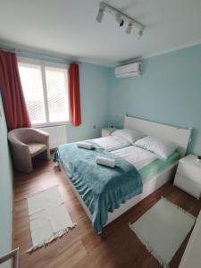 a bedroom with a bed and a chair and windows at Dorka Villa in Tihany