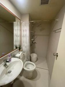 ein Badezimmer mit einem weißen WC und einem Waschbecken in der Unterkunft Azure Urban Resort - By Ground Zero One in Manila