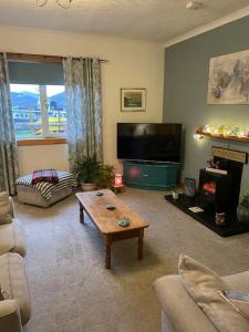 a living room with a tv and a coffee table at Station Cottage in Fort William