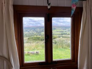 a window with a view of a field of grass at Shepherd's Hut Bilsdale in Chop Gate