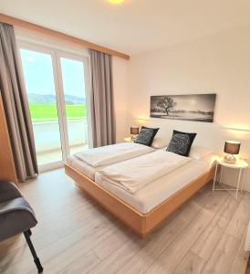 a bedroom with a large bed and a large window at Ferienpark Scheiber in Unterburg am Klopeiner See