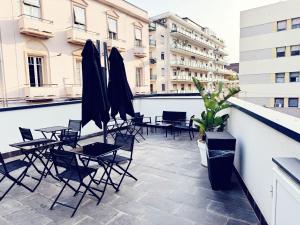 un patio con sedie e ombrelloni su un balcone di 8room Hotel a Catania