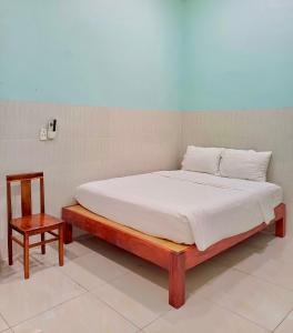 ein Bett mit einem Holzrahmen und einem Stuhl in einem Zimmer in der Unterkunft NGUYỆT MINH HOTEL in Ấp Phú Lợi