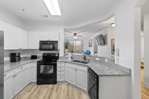 a kitchen with white cabinets and black appliances at Havens #1123 condo in North Myrtle Beach