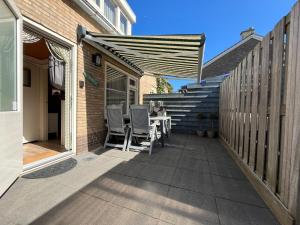 een patio met een tafel, stoelen en een trap bij Zomerhuis Beach EnJoy in Egmond aan Zee