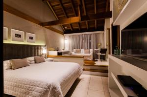 a bedroom with a bed and a living room at Solar Mirador Exclusive Resort e SPA in Praia do Rosa