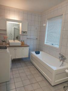 La salle de bains blanche est pourvue d'une baignoire et d'un lavabo. dans l'établissement Øren apartment, à Drammen