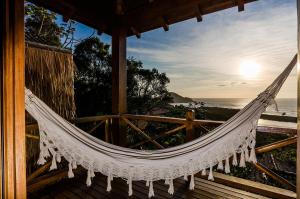 a hammock on a porch overlooking the ocean at Solar Mirador Exclusive Resort e SPA in Praia do Rosa