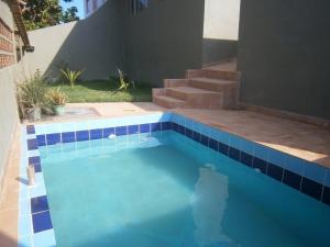 una piscina con azulejos azules en el lateral de una casa en Apt. de Setiba - HOSPEDARIA OCA RUCA en Guarapari