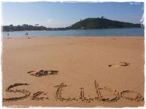 a sign written in the sand on a beach at Apt. de Setiba - HOSPEDARIA OCA RUCA in Guarapari