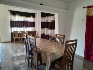 comedor con mesa, sillas y ventanas en Harrisline Holiday Homes, en Nuwara Eliya