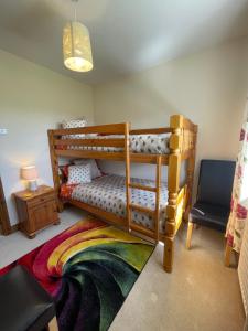 a bedroom with a bunk bed and a chair at Honeycomb Cottage - a quiet, charming, cosy retreat in the countryside only 2 miles from one of Cornwall's best beaches in Truro