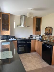 a kitchen with black appliances and wooden cabinets at Grandma's Honeycomb Cottage - a quiet, charming, cosy retreat in the countryside only 2 miles from one of Cornwall's best beaches in Truro