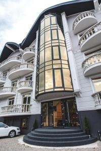 um edifício branco com janelas e um carro estacionado em frente em Olimp Hotel em Bukovel