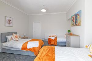 a bedroom with two beds with orange sheets at Scott House - Contractor Friendly - Sleeps 7 in Liverpool