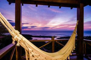 a hammock in a room with a view of the ocean at Solar Mirador Exclusive Resort e SPA in Praia do Rosa