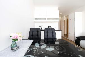 a dining room with a glass table and black chairs at Studio W/Balcony @ManoŠventovė, By Cohost in Palanga