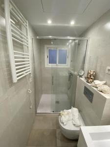 a white bathroom with a shower and a toilet at El Velero una terraza al mar in Calafell