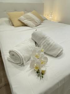 Una cama blanca con toallas y flores. en El Velero una terraza al mar, en Calafell