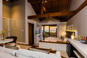 a living room with two beds and a dining table at Solar Mirador Exclusive Resort e SPA in Praia do Rosa