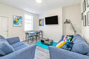 a living room with a blue couch and a table at Scott House - Contractor Friendly - Sleeps 7 in Liverpool