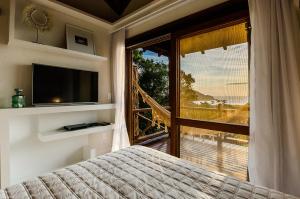 a bedroom with a bed and a large window with a view at Solar Mirador Exclusive Resort e SPA in Praia do Rosa