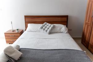 um quarto com uma grande cama branca e uma cabeceira em madeira em Cozy Bedroom, shared bathroom -Gzira em Il-Gżira