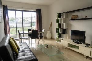 uma sala de estar com um sofá, uma televisão e uma mesa em Cozy Bedroom, shared bathroom -Gzira em Il-Gżira