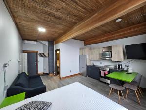 cocina y sala de estar con mesa verde en Lofts Hôtel Gaspésie, en Sainte-Anne-des-Monts